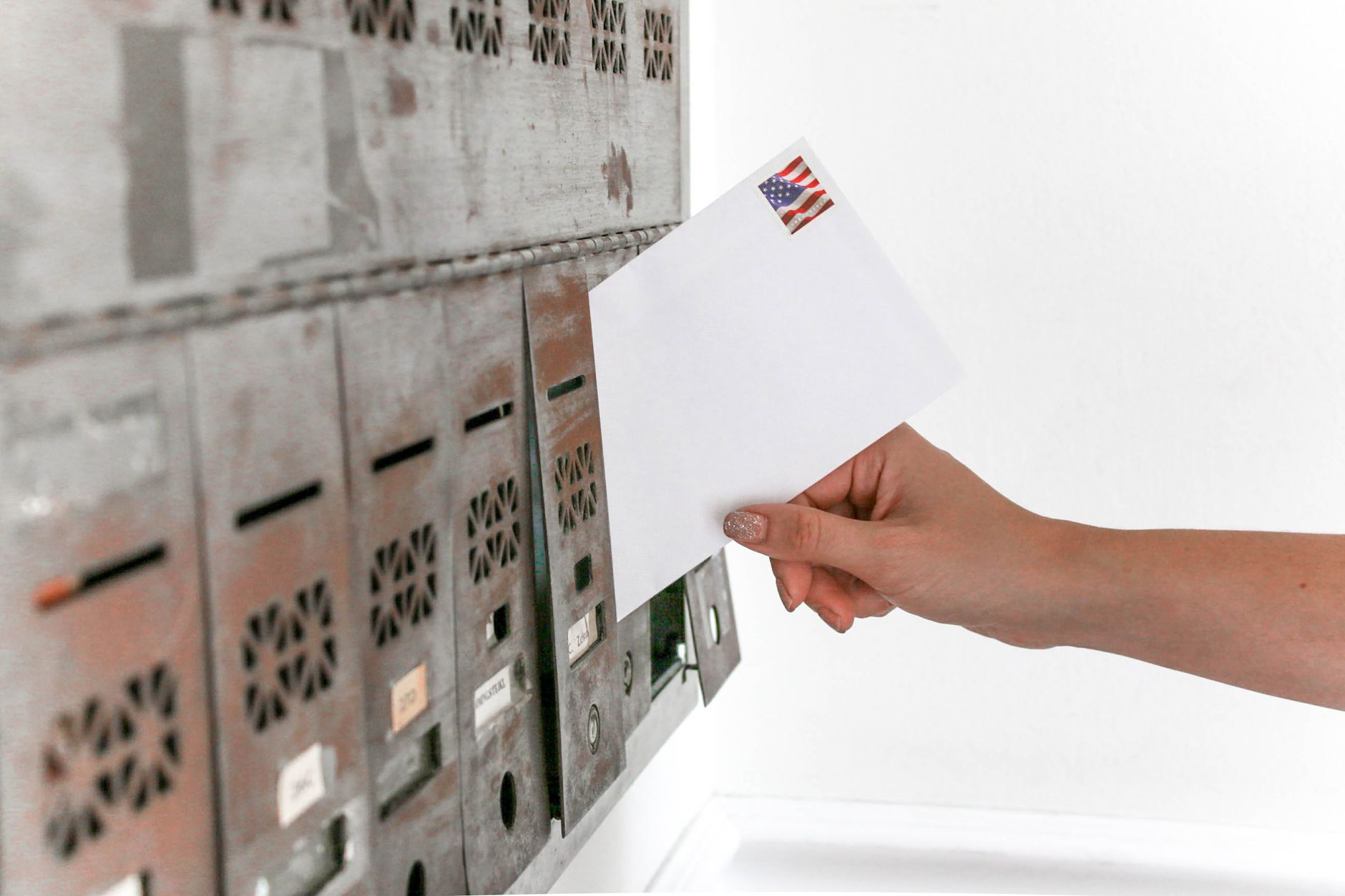 Hand posting an envelope into a mailbox