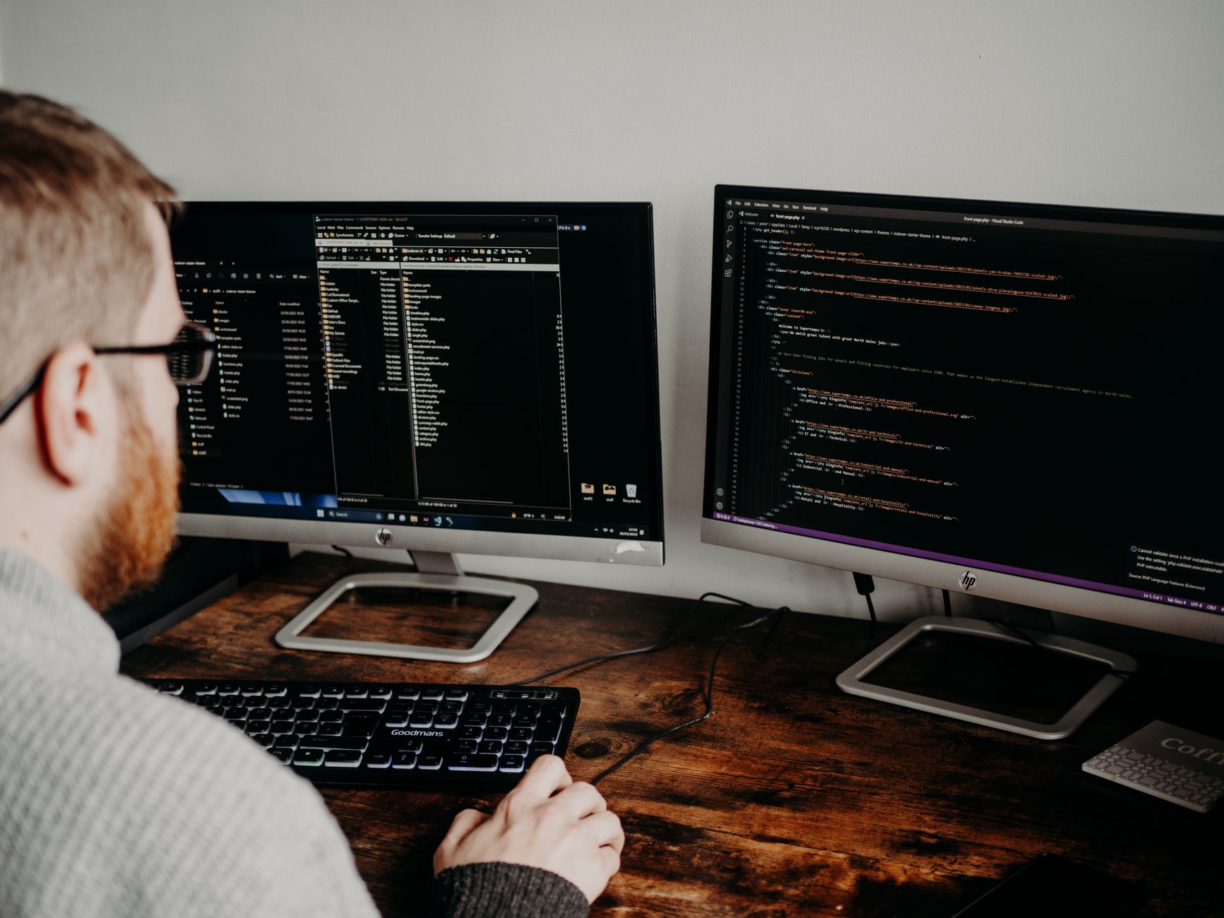 Developer writing code on dual monitors