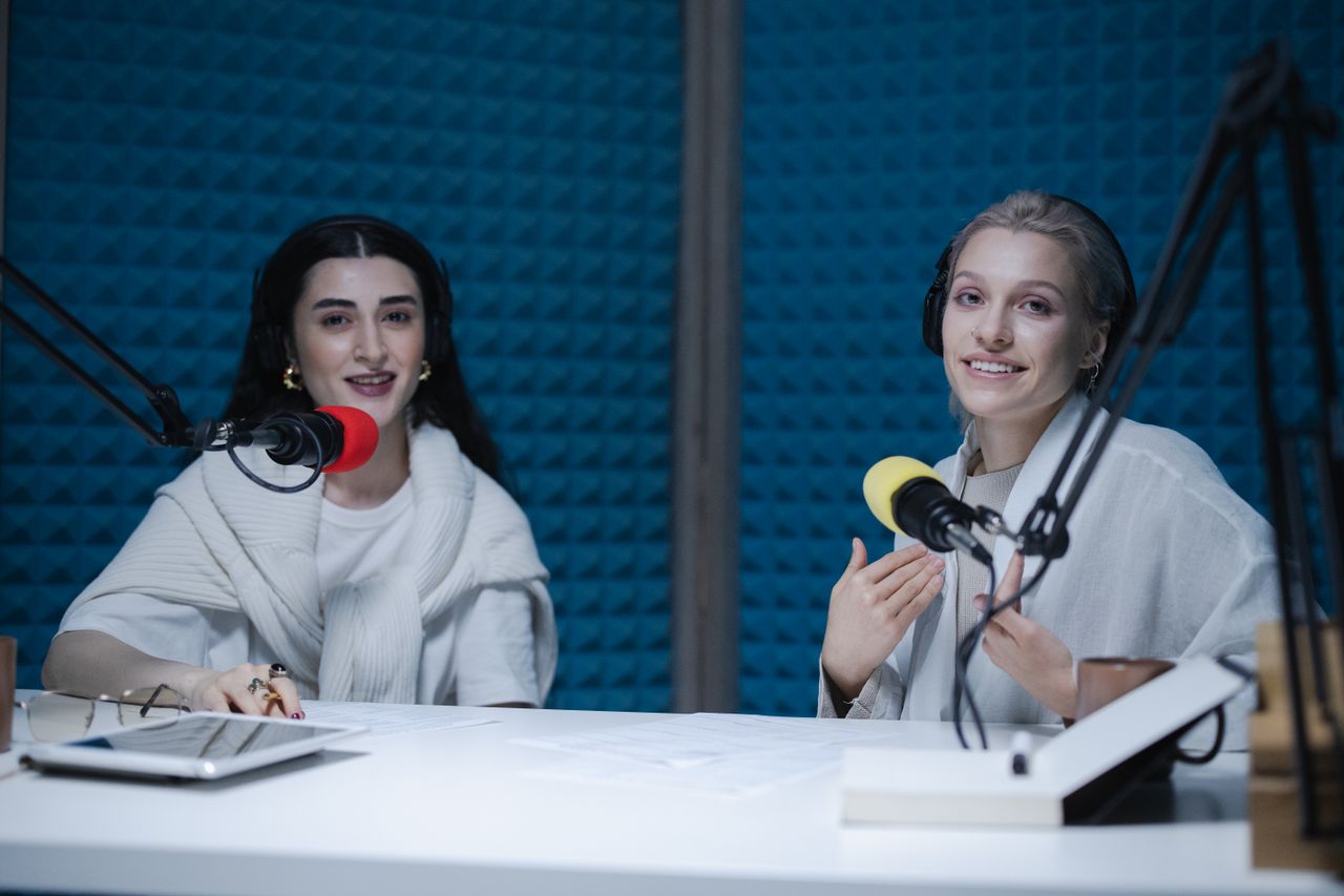 Two podcast hosts recording in a studio